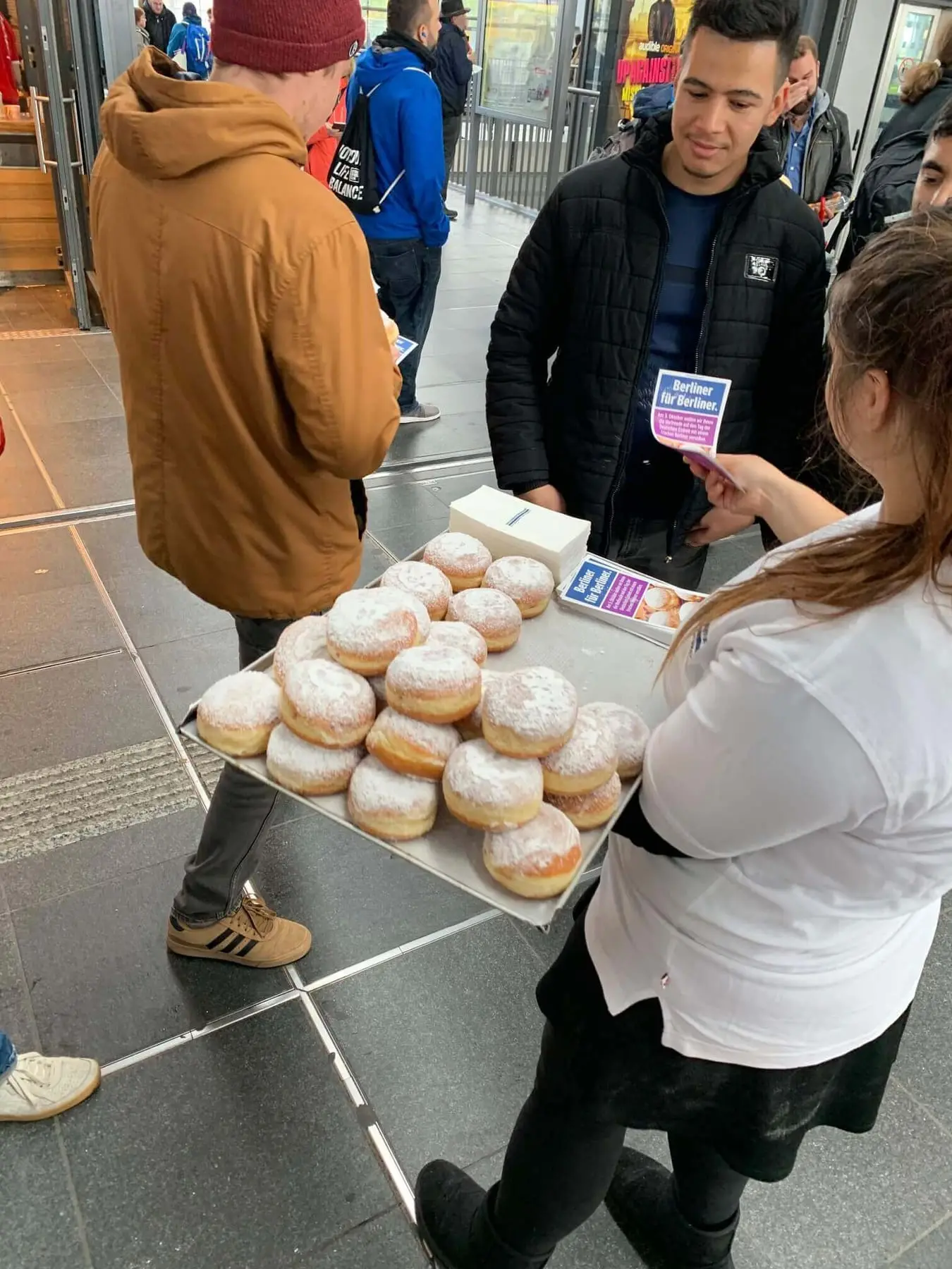 Ausgabe von Pfannkuchen an Passanten in der Bahnhofshalle