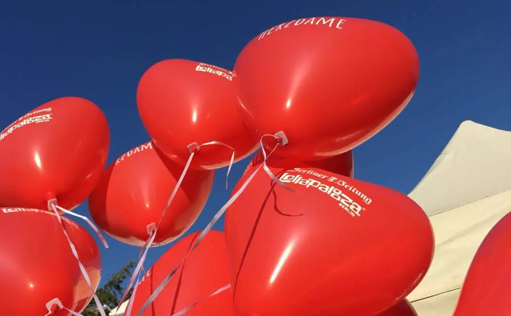 Bedruckte rote Herzballons vor blauem Himmel
